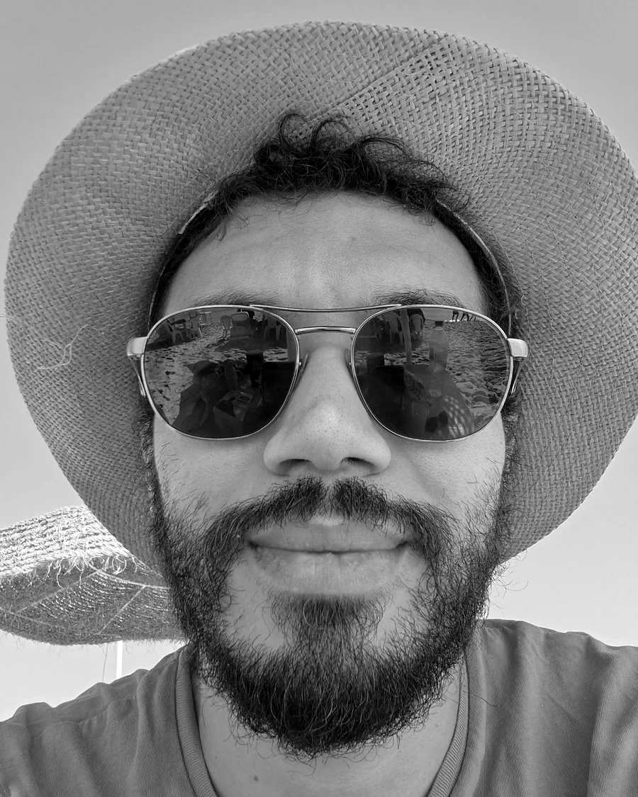 Mohamed Melki, photographed outdoors in sunglasses and a straw hat.